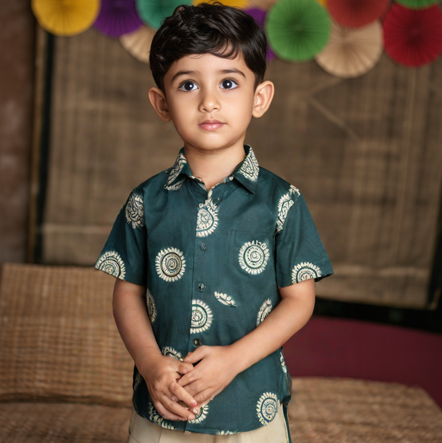 Child wearing a green patterned shirt with colorful decorations in the background